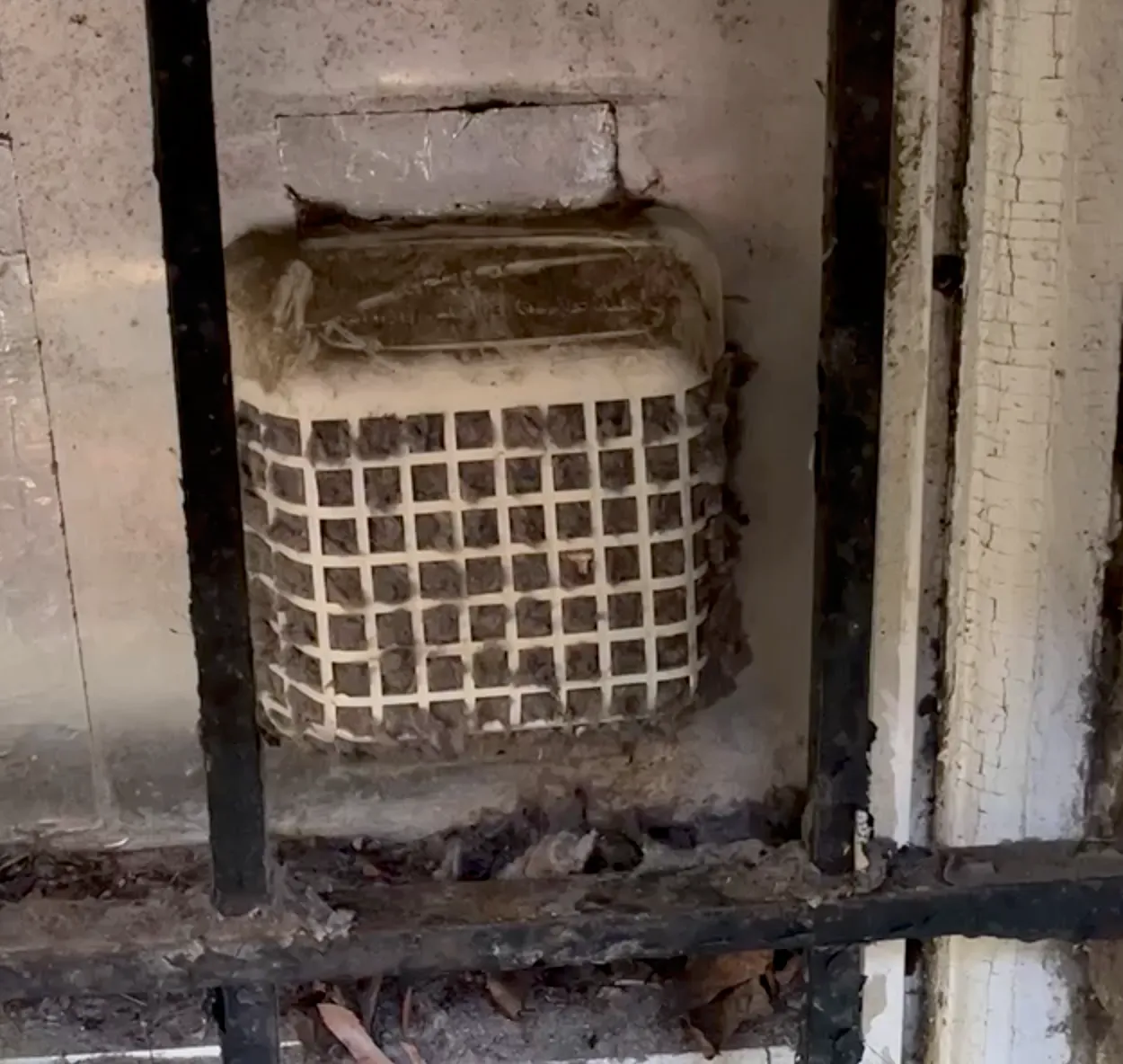 A Bowie Dryer Vent Cleaning owner removing a dryer vent hood packed with lint and debris behind a screened cover, before cleaning.