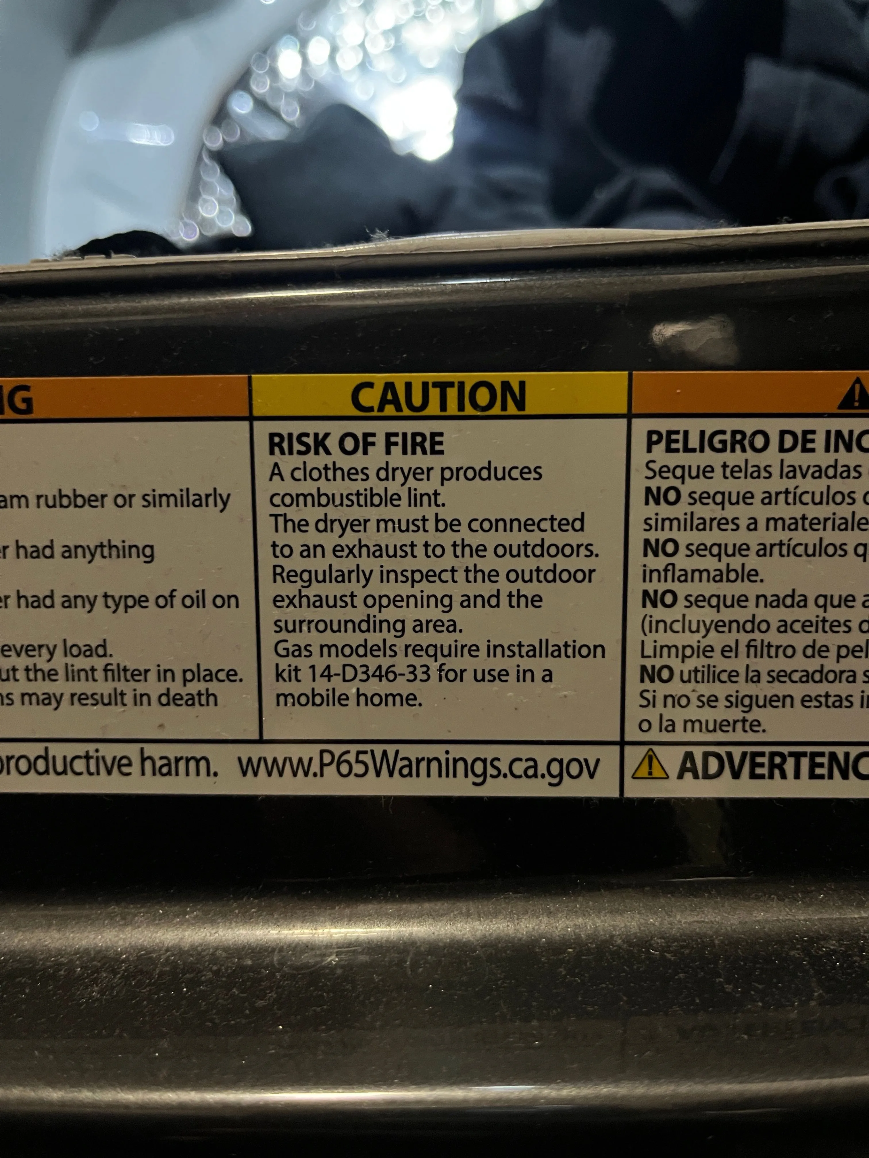 Manufacturer's caution label on a clothes dryer warning of fire risk from combustible lint.